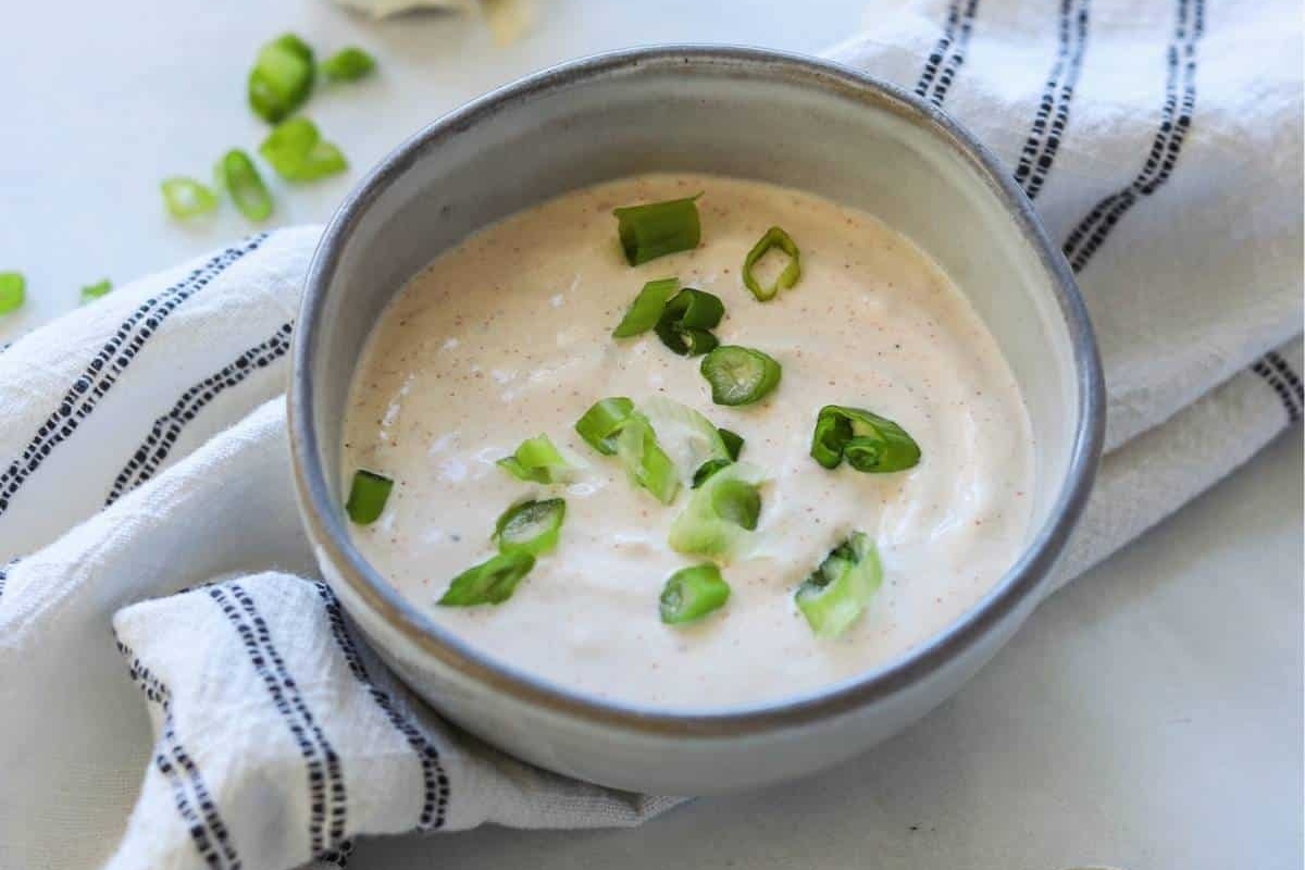 A bowl of creamy garlic dip with green onions.