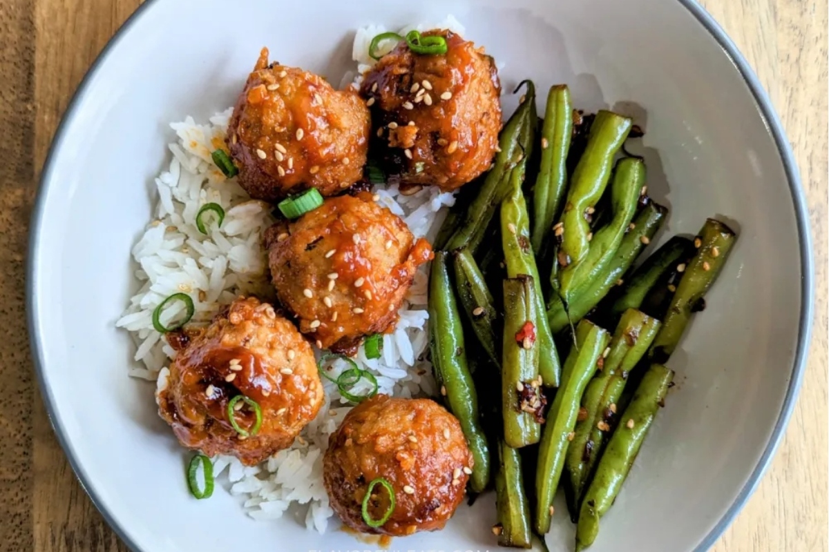 A white plate with meatballs, green beans and rice.