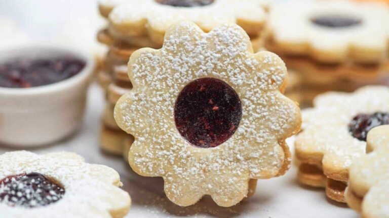 A plate of cookies with jam and powdered sugar.