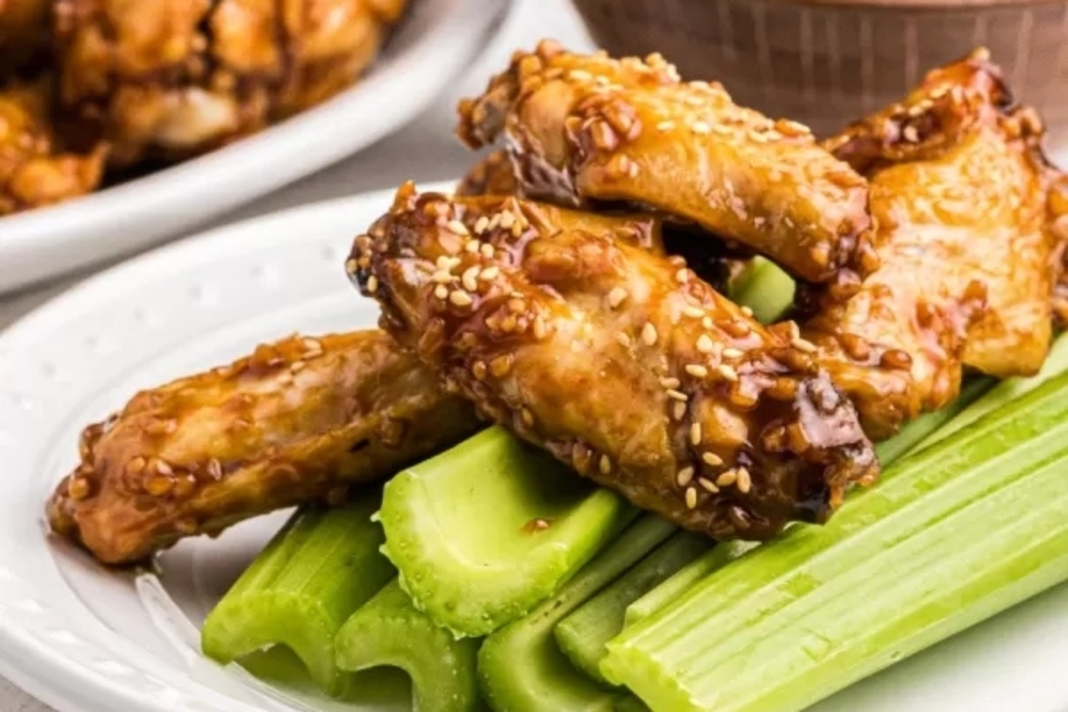 A plate with chicken wings and celery.