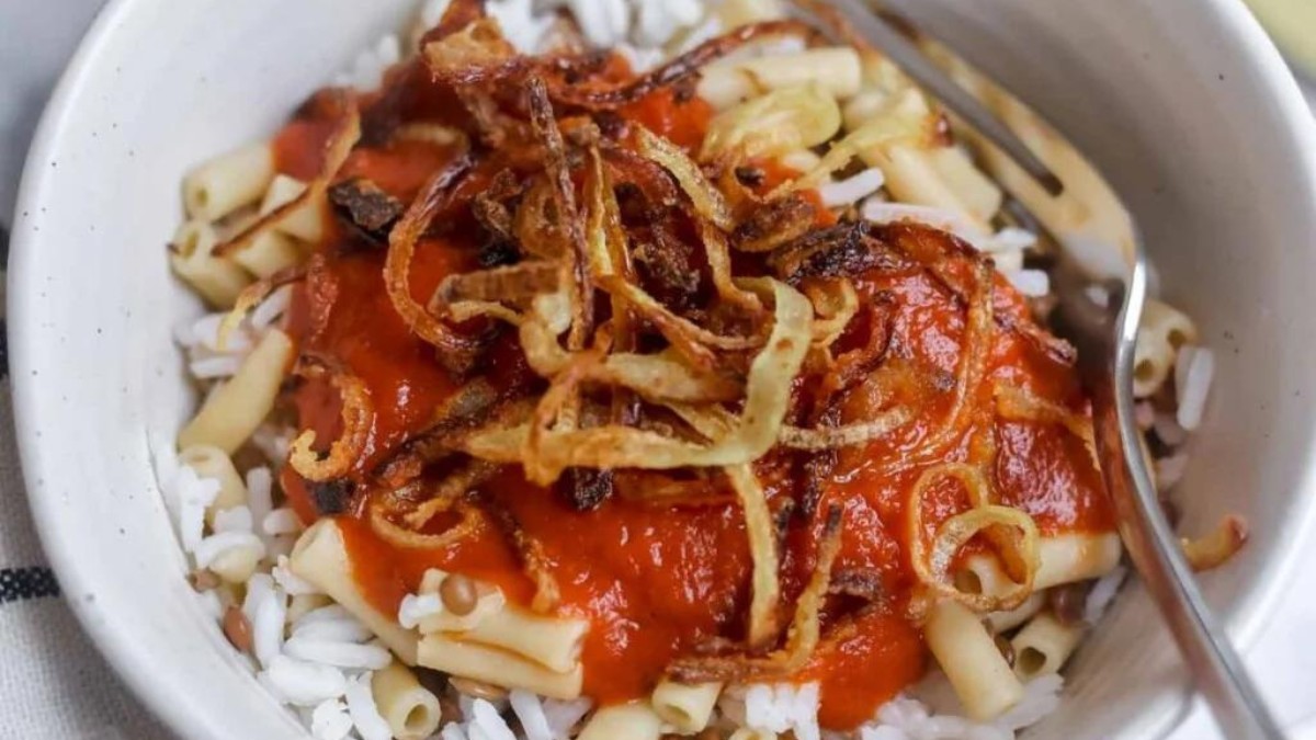Bowl of rice with onions and red sauce.