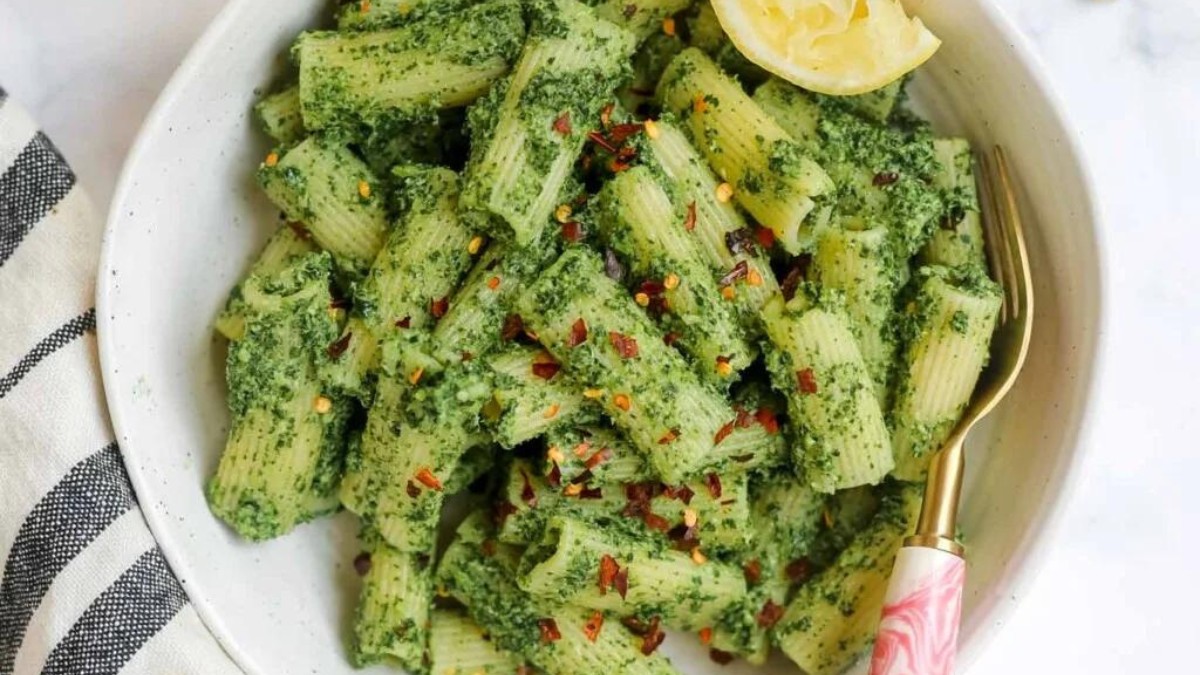 Green bowl of kale pesto pasta with lemon.