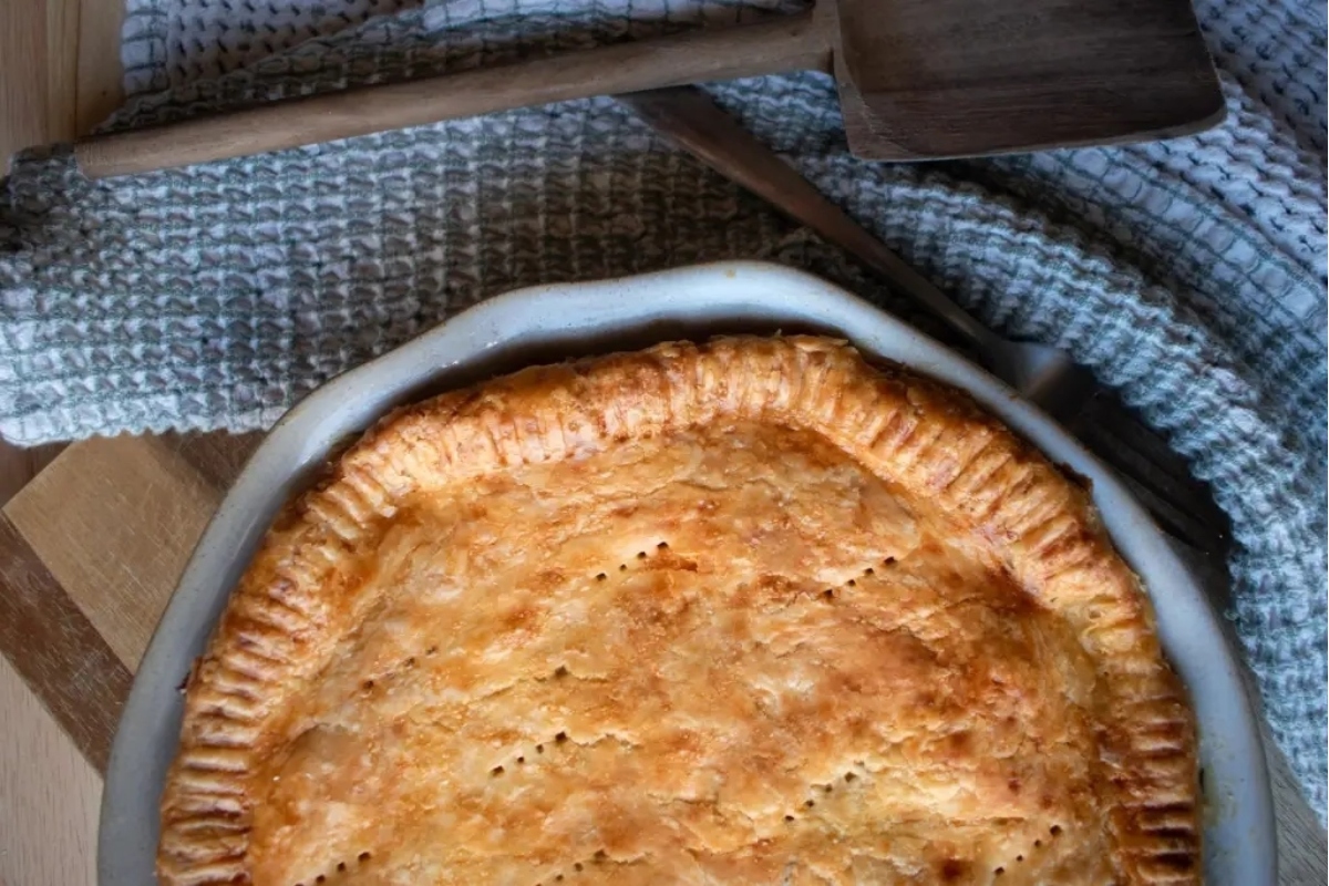 A pie in a dish with a wooden spoon.