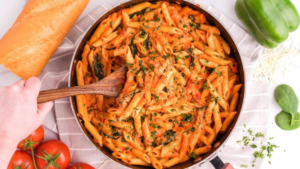 Skillet of penne rosa pasta with wooden spoon.