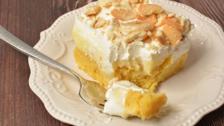 A slice of banana pudding cake on a plate with a fork.