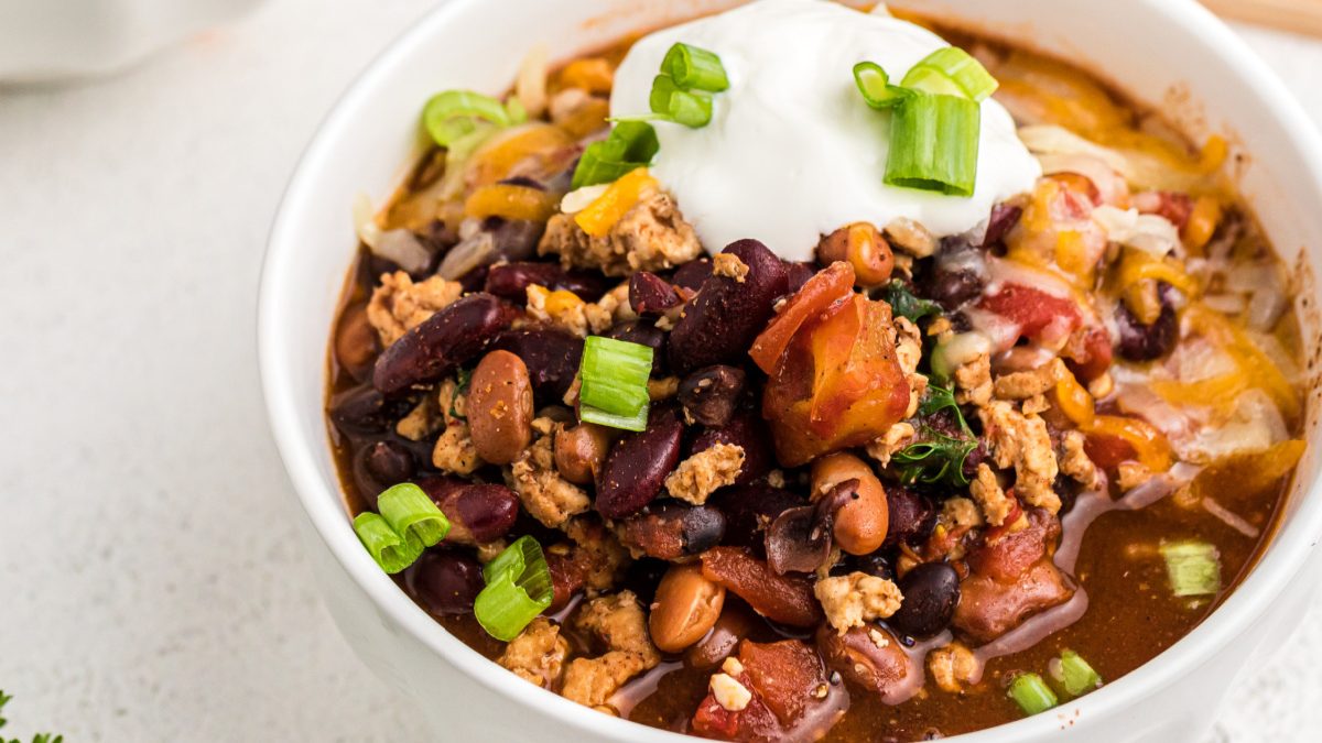 Turkey chili in a bowl topped with sour cream and green onions.
