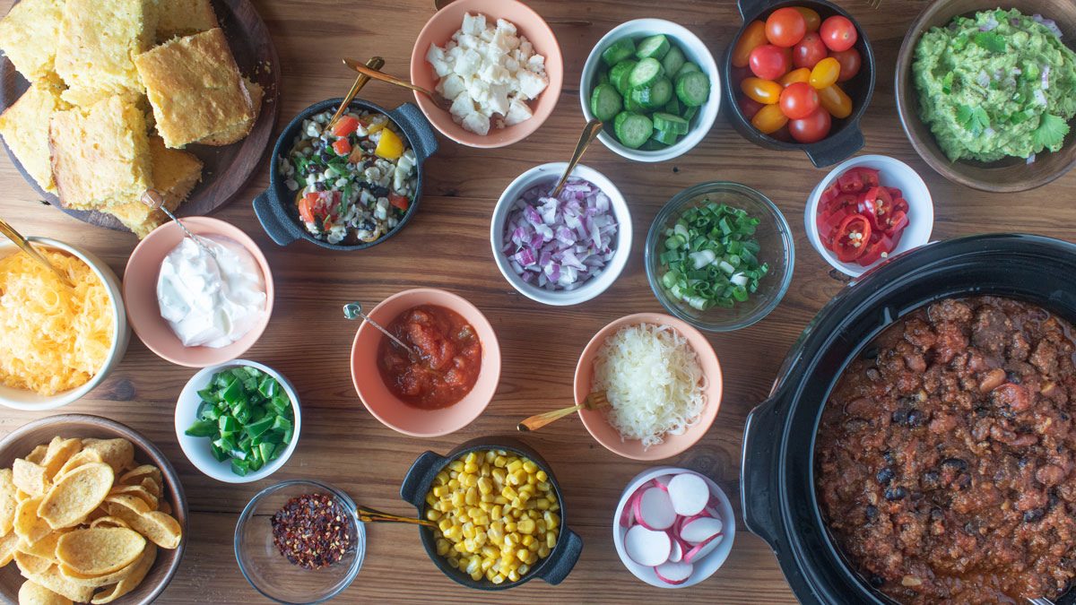 A pot of chili and lots of little bowls filled with toppings.