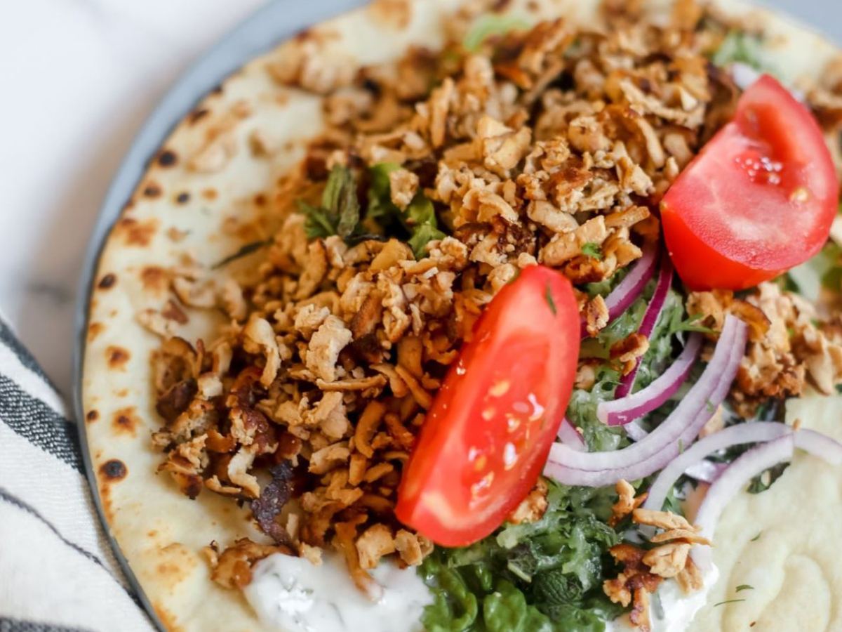 Open flatbread topped with tomatoes, tofu and onion.