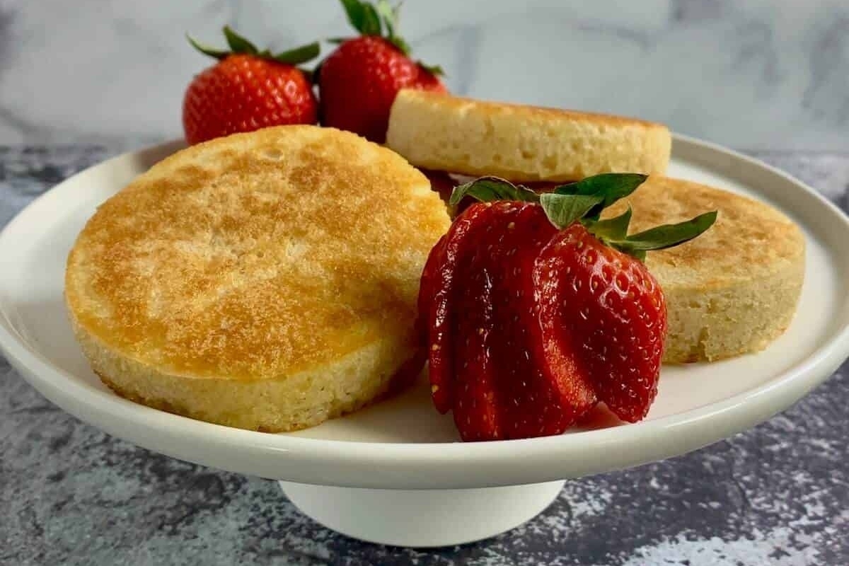A white plate with strawberries and crumpets on it.