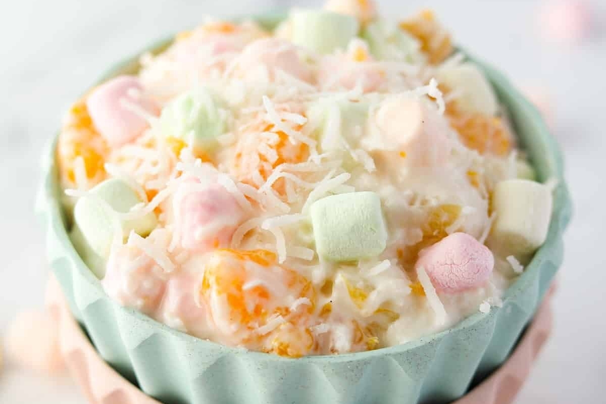 A bowl of ambrosia salad with marshmallows and shredded coconut.