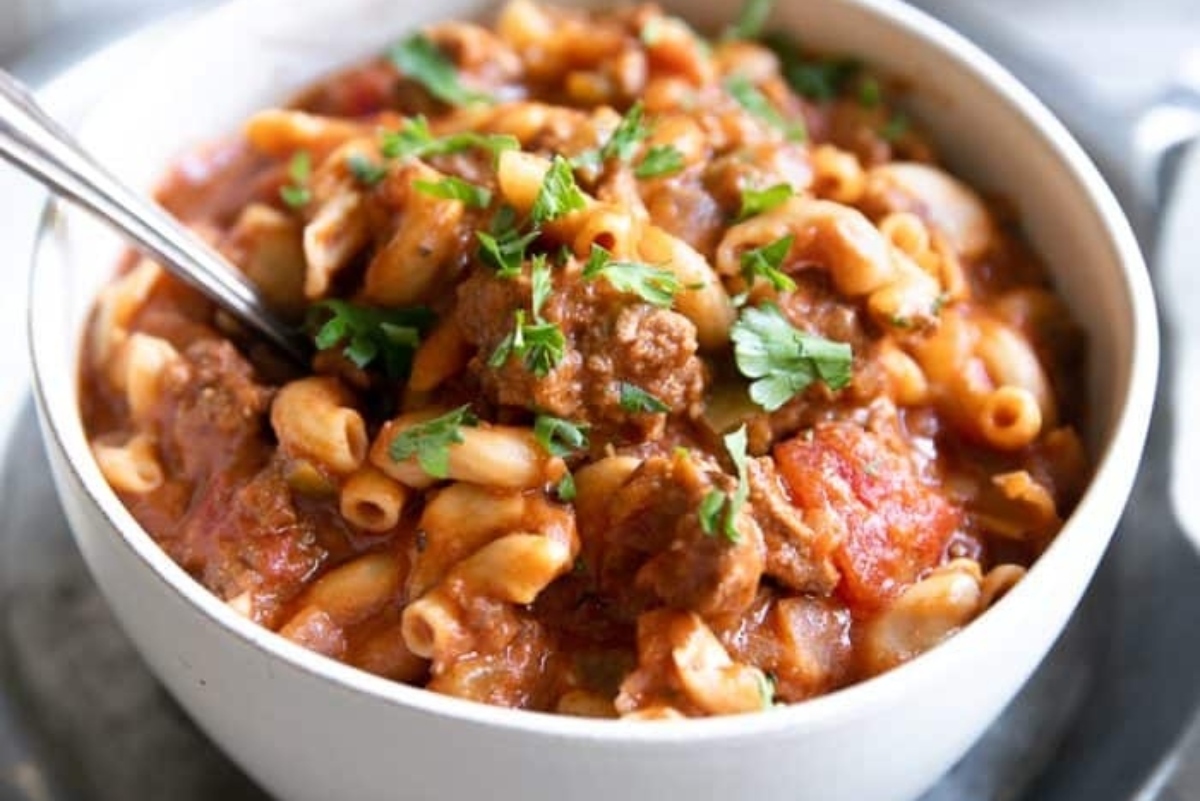A bowl of pasta with meat and tomatoes.