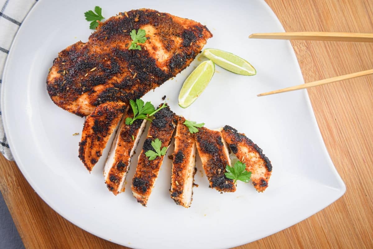 Grilled chicken on a white plate with chopsticks.