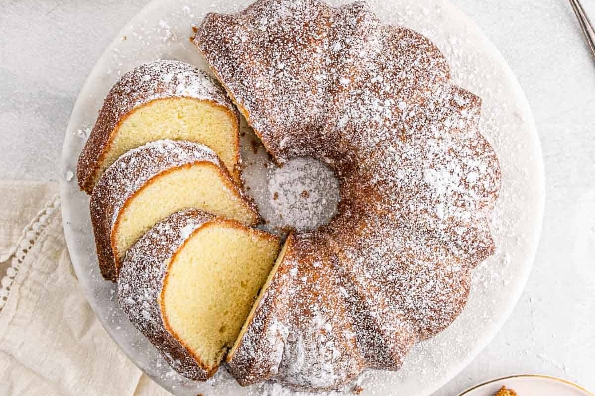 Sliced bundt cake with powdered sugar on a white plate.