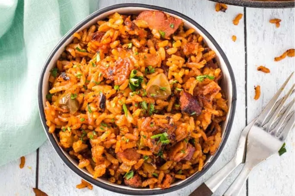 A bowl of rice and sausage with a fork on a wooden table.