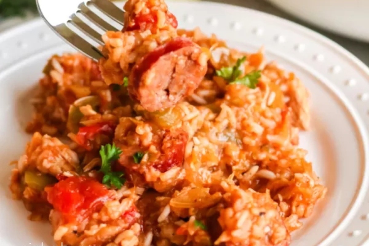 A fork is being used to eat a plate of rice and sausage.
