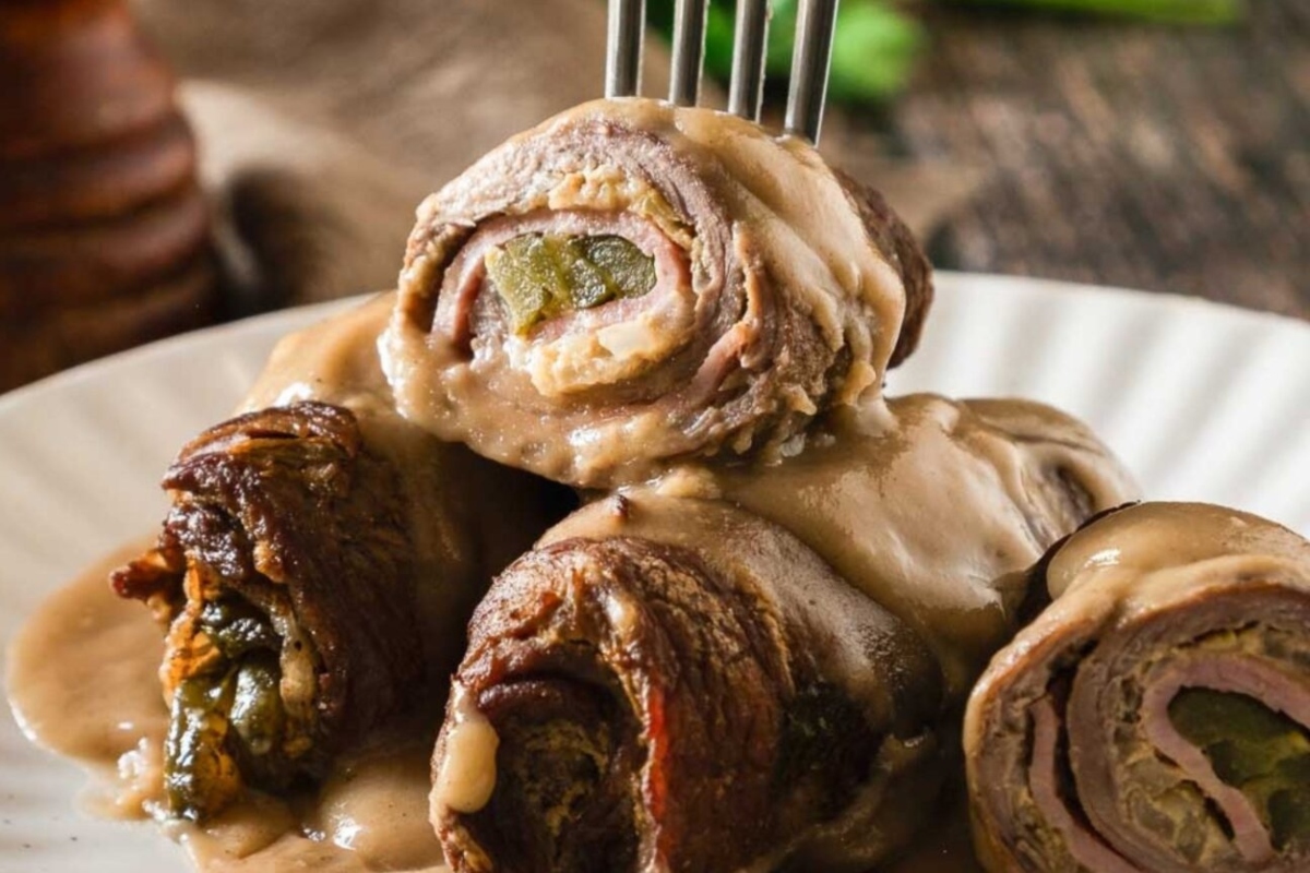 A fork on a plate of meat rolls.