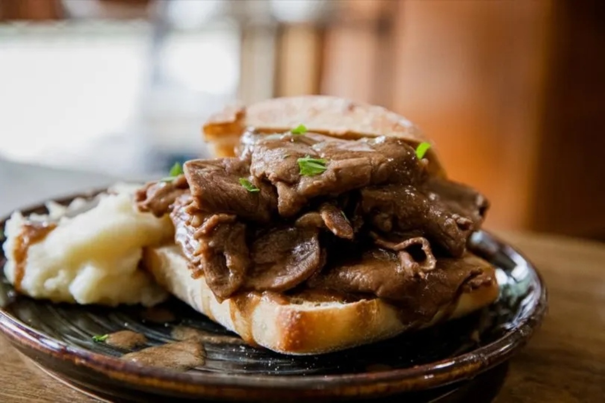 An open-faced roast beef sandwich with mashed potatoes on the side.