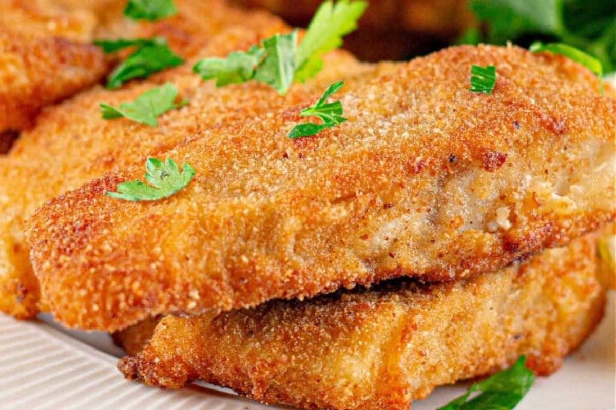 Fried fish fillets on a white plate.
