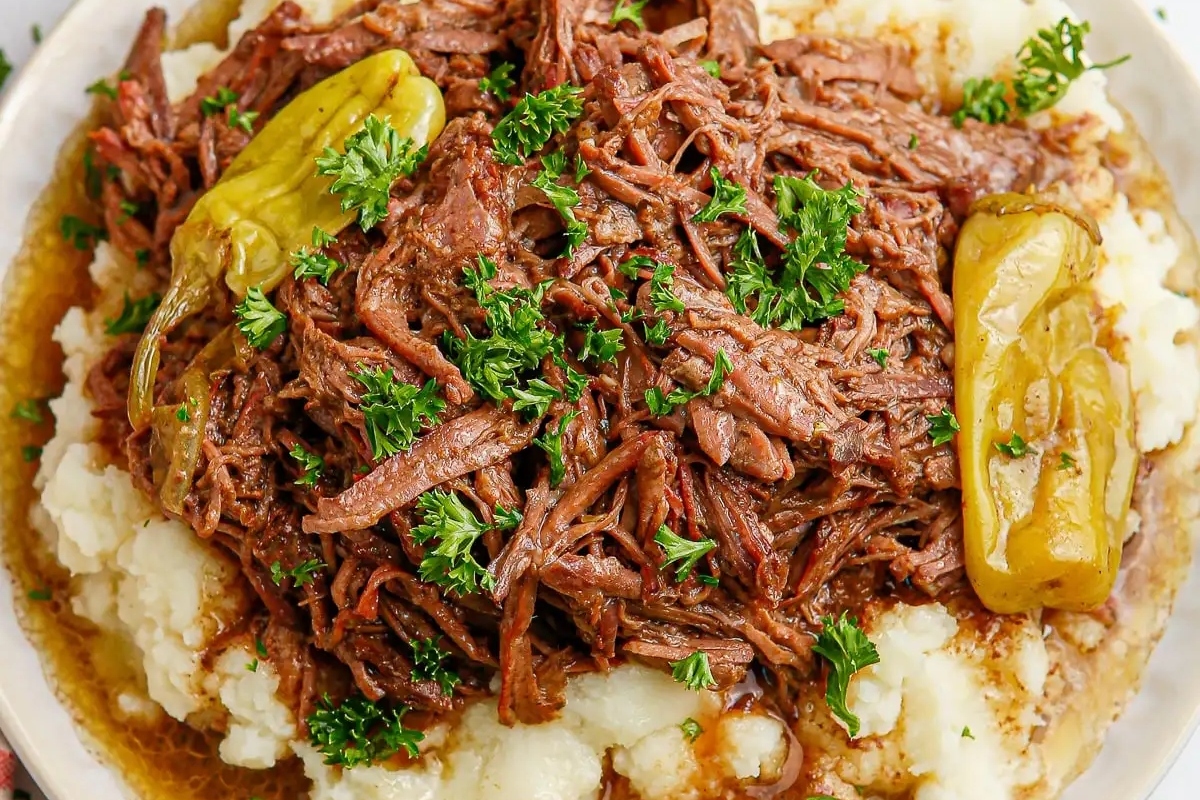 A plate with mashed potatoes and beef on it.