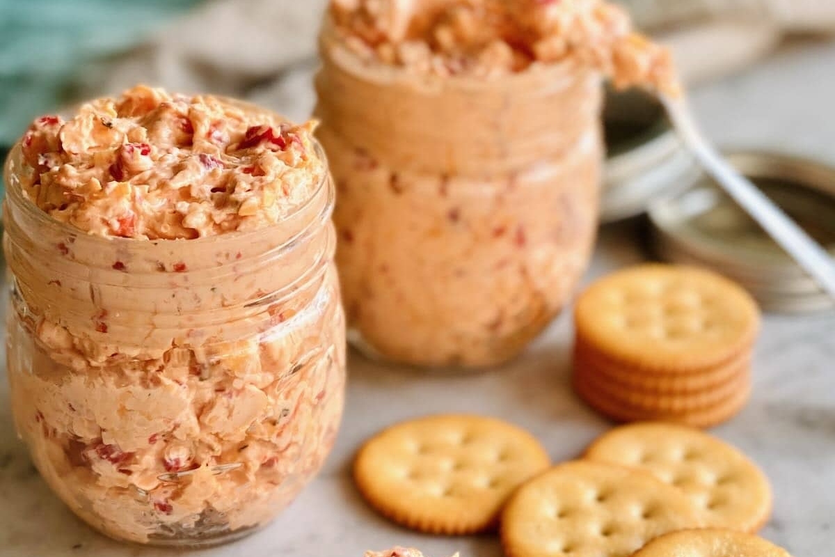 Two jars of pimento cheese dip with crackers.