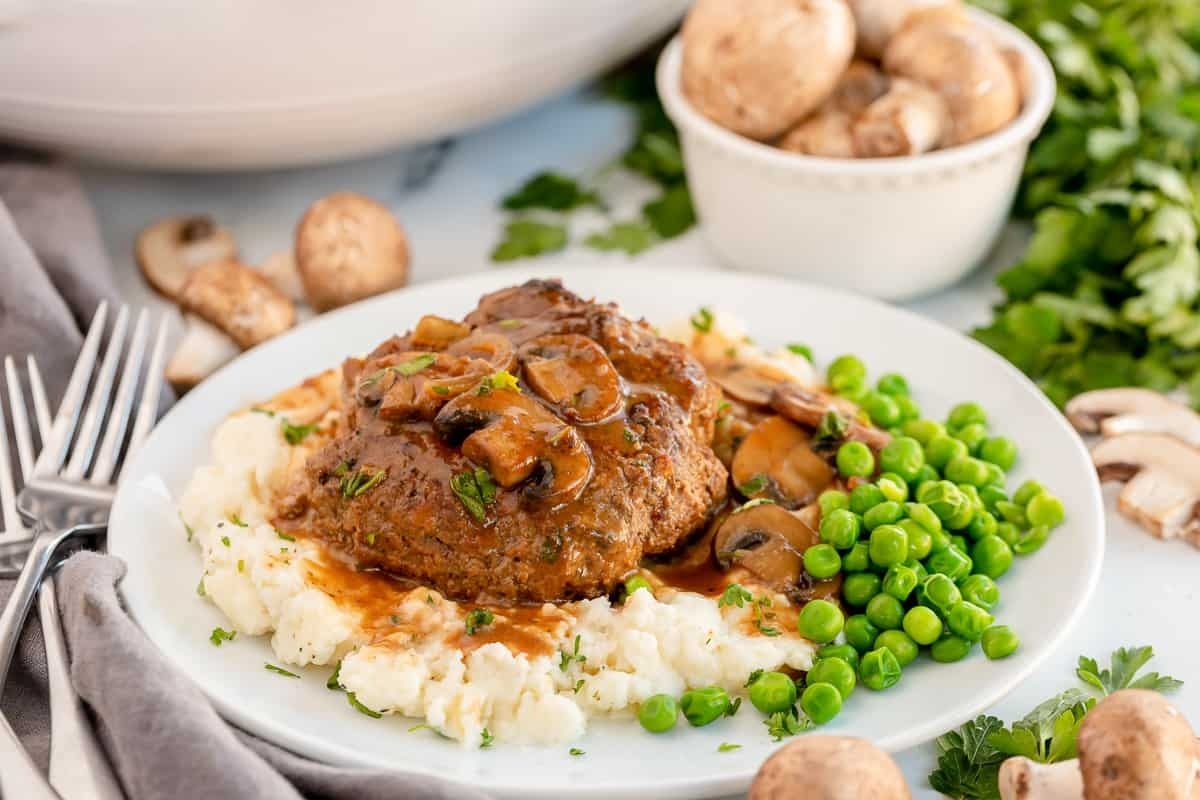 Meatloaf with mushrooms and peas on a plate.