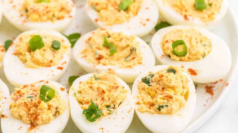 A platter of salsa deviled eggs garnished with paprika and green onions.