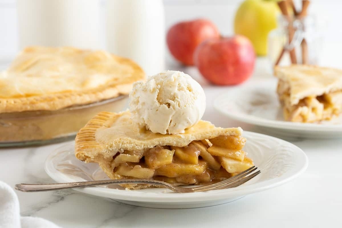 A slice of apple pie on a plate with ice cream.