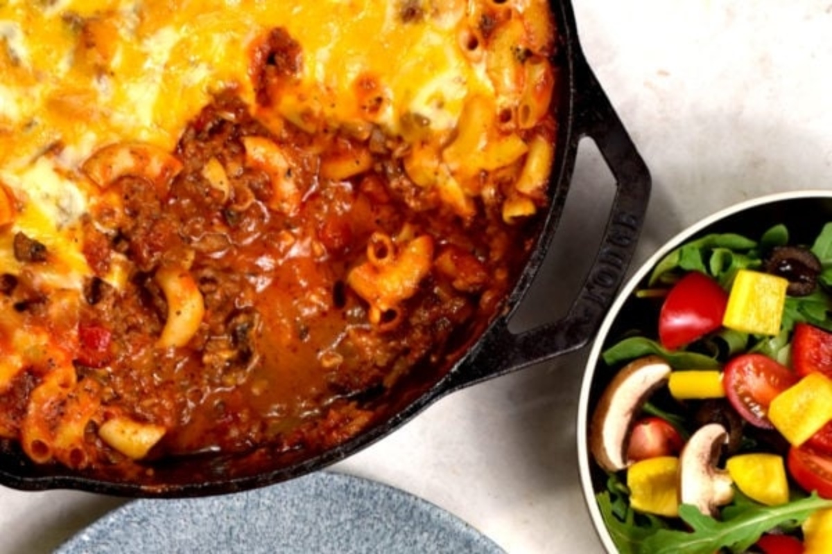 Baked pasta dish in a cast iron skillet served next to a fresh salad.