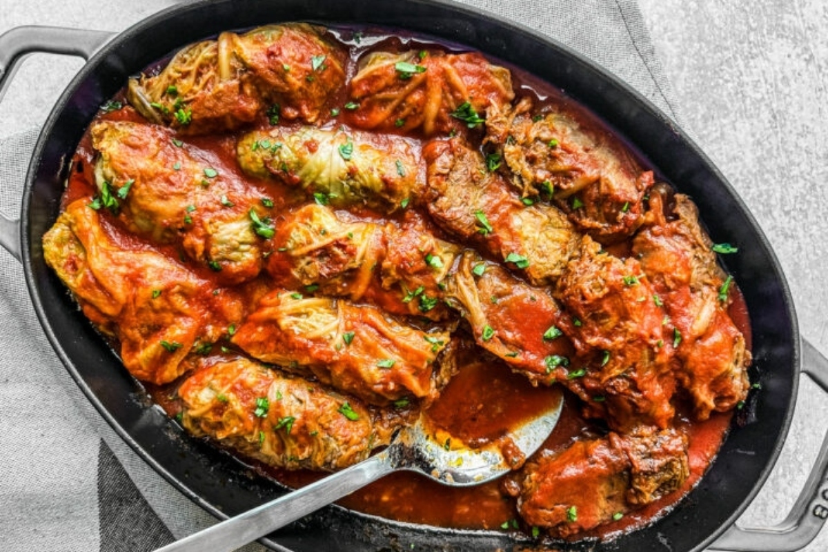 Stuffed cabbage rolls in a skillet with sauce.