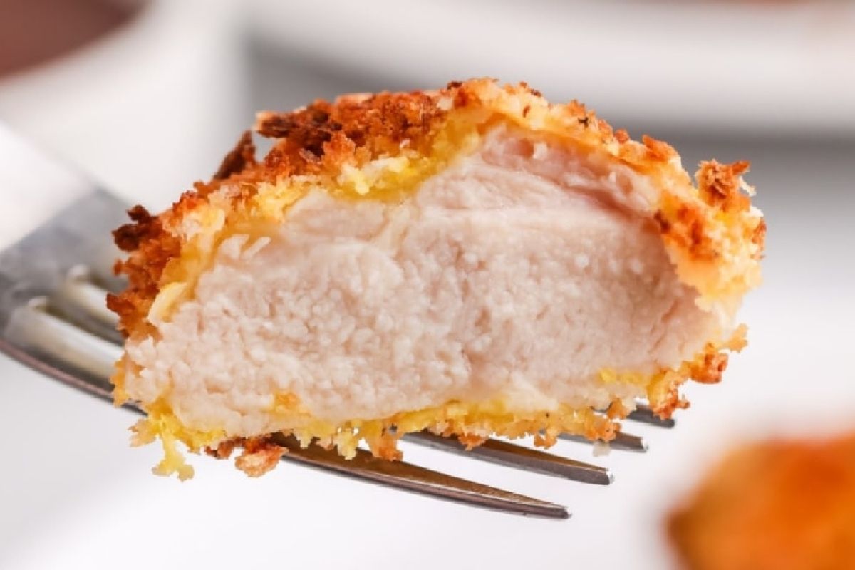 23 Finger-Lickin' Good Chicken Thigh Recipes That Are Simply Irresistible 1 A close-up of a breaded chicken piece being held by a fork, showcasing its texture and cooked interior, perfect for air fryer dinner recipes.