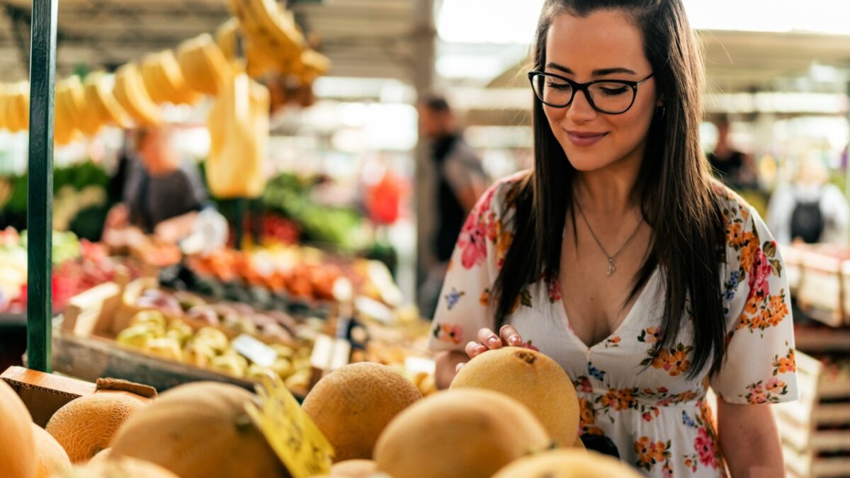 The 13 Best Types of Melons to Try 1 A smiling girl at the market selects, taps, and smells a melon